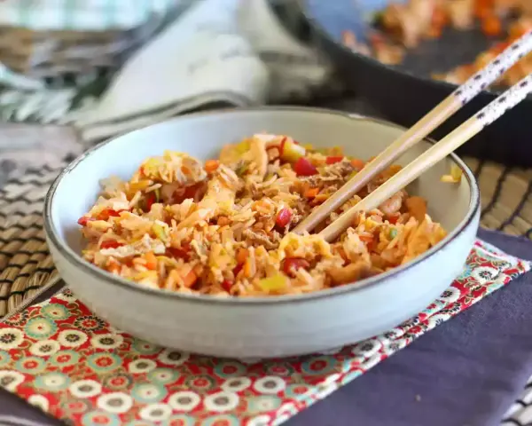 Miseczka pełna aromatycznego nasi goreng z warzywami i kawałkami mięsa, gotowa do jedzenia pałeczkami.