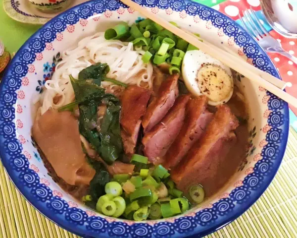 Pyszny ramen z kaczki z makaronem, jajkiem, szpinakiem i szczypiorkiem.