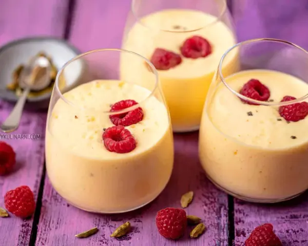Pyszny jogurt z mango, udekorowany malinami i kardamonem, kusi swoim tropikalnym smakiem.