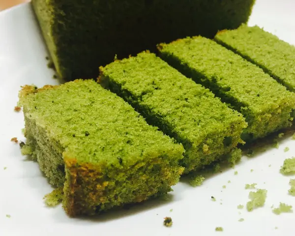 Puszyste ciasto matcha pokrojone w prostokątne kawałki, ułożone na białym talerzu.