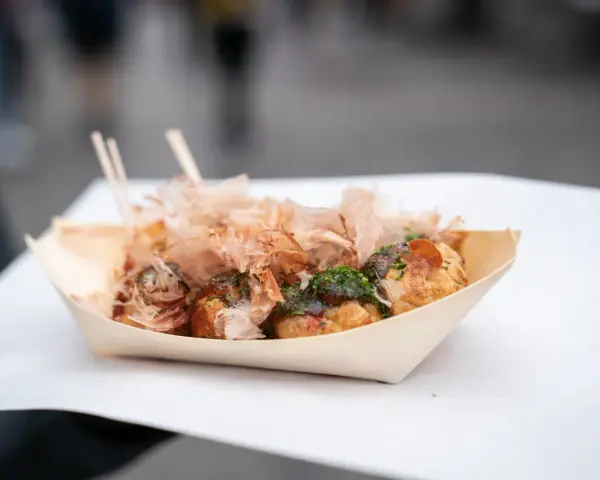 Pyszne takoyaki, czyli japońskie kulki z ośmiornicą, posypane płatkami bonito i zieloną posypką. Idealny japoński street food na wynos.