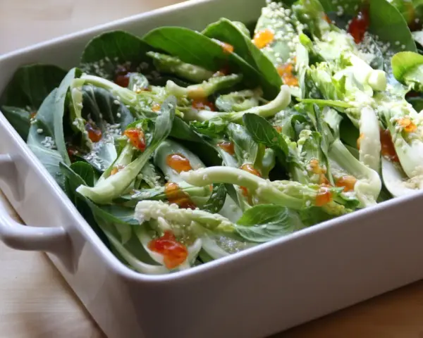 Pyszna kapusta pak choi po tajsku, polana sosem i posypana sezamem, w białej ceramicznej misie.