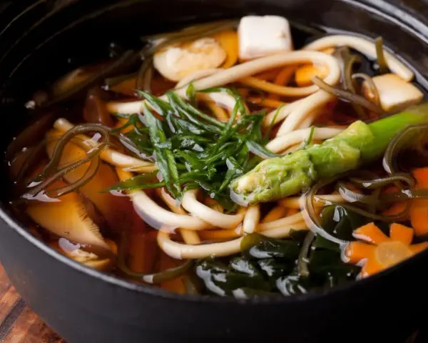 Aksamitny bulion dashi, w którym pływają grube kluski udon, tofu, marchewki w kształcie kwiatków, zielone warzywa i wodorosty. Pyszne i zdrowe danie.