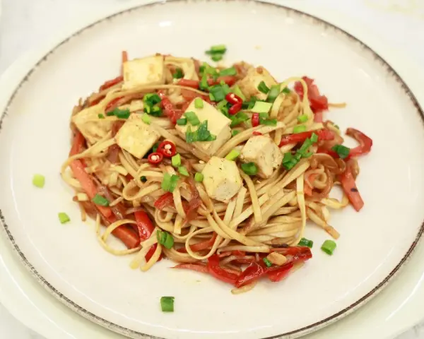 Pyszny makaron chow mein z kostkami tofu, papryką i szczypiorkiem.