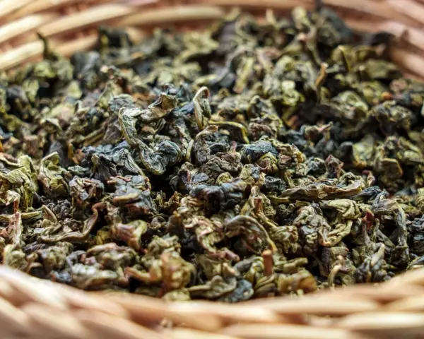 Suszone liście herbaty gunpowder w wiklinowym koszyku. Odkryj jej niezwykłe właściwości!