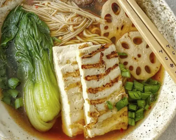 Aksamitny vege ramen z grillowanym tofu, pak choi, grzybami enoki i plasterkami lotosu. Idealny na chłodny wieczór.