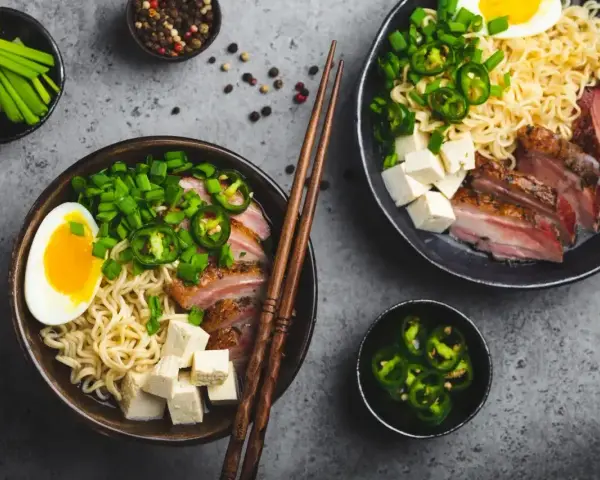 Pyszny ramen wołowy przepis: makaron, plastry mięsa, jajko, tofu, szczypiorek i papryczki jalapeño.
