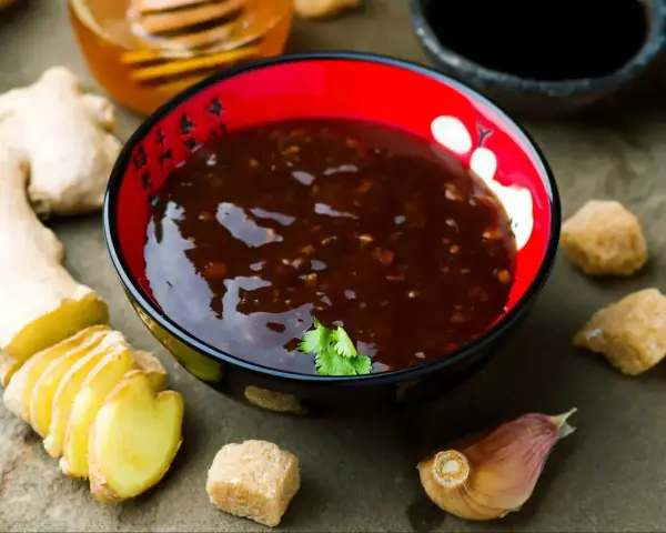Aksamitny sos teriyaki w misce, obok świeży imbir, czosnek i brązowy cukier. Idealny do wieprzowiny.
