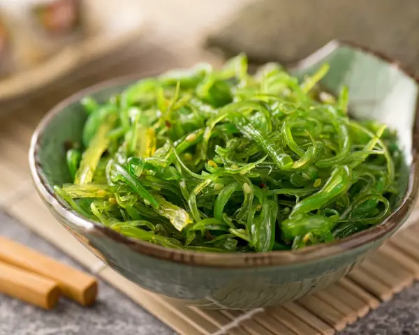 Miseczka zielonej sałatki z wodorostów wakame, idealna do sushi. Prosty wakame przepis na zdrową przekąskę.