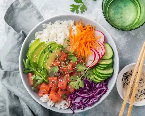 Kolorowy poke bowl: ryż, łosoś, awokado, marchewka, rzodkiewka, ogórek i czerwona kapusta. Idealny posiłek, który zaspokoi głód.