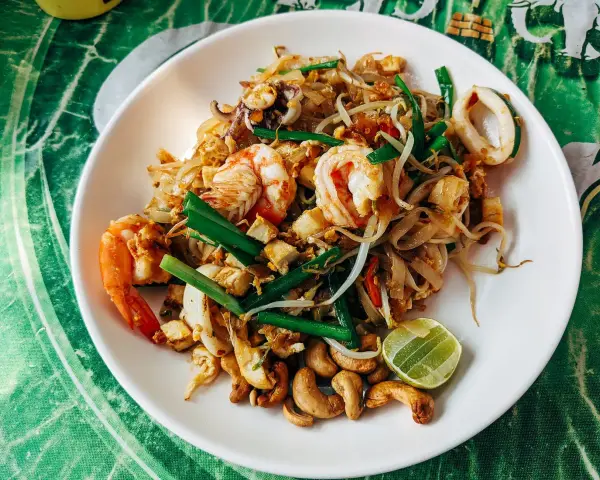 Pad thai z krewetkami, kalmarami, kiełkami i orzechami nerkowca. Widać też kawałek limonki, idealne pad thai składniki.