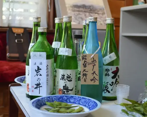 Butelki z japońskim alkoholem, idealne, gdy szukasz, czym zastąpić sake. Obok miseczka z edamame.