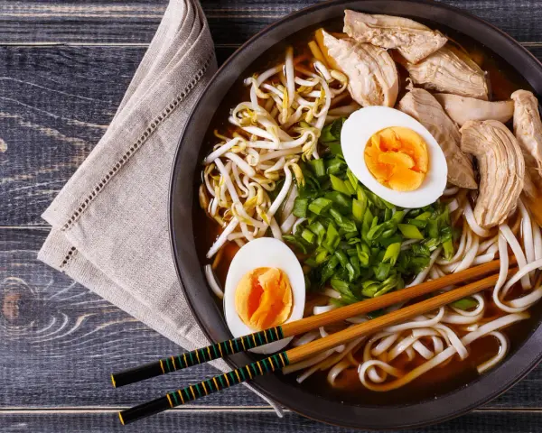 Pyszny shoyu ramen z kurczakiem, jajkiem na twardo, kiełkami fasoli mung i szczypiorkiem.