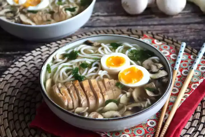 Pyszne ramen z kurczakiem, jajkiem na pół i grzybami. Aromatyczny bulion i delikatny kurczak tworzą idealne danie.