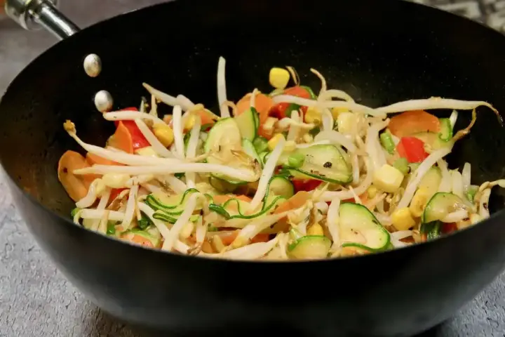 Kolorowe warzywa teriyaki w woku: kiełki fasoli mung, cukinia, marchewka, papryka i kukurydza.