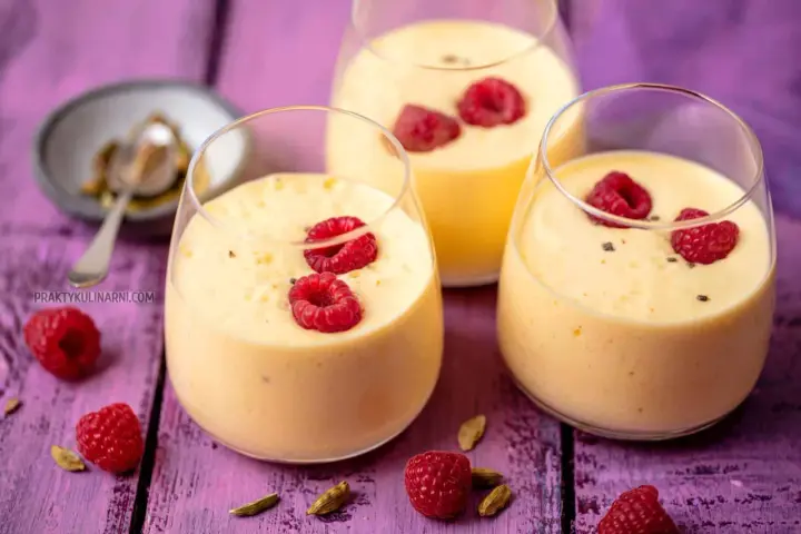 Pyszny jogurt z mango, udekorowany malinami i kardamonem, kusi swoim tropikalnym smakiem.