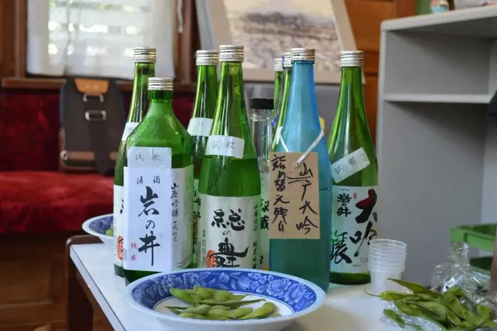 Butelki z japońskim alkoholem, idealne, gdy szukasz, czym zastąpić sake. Obok miseczka z edamame.
