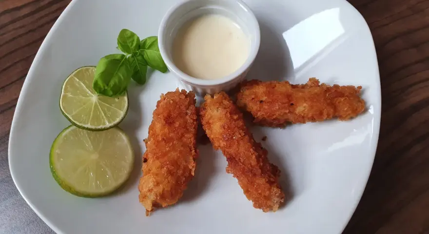 Chrupiąca ryba w panko, podana z sosem i limonką, wygląda apetycznie.