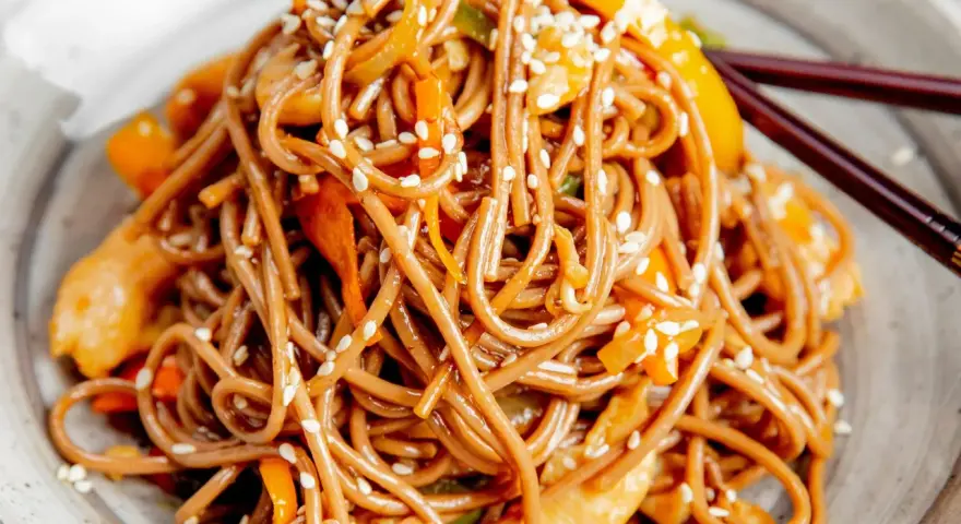Soba z kurczakiem i warzywami, posypana sezamem. Pyszny przepis na soba, idealny na szybki obiad.
