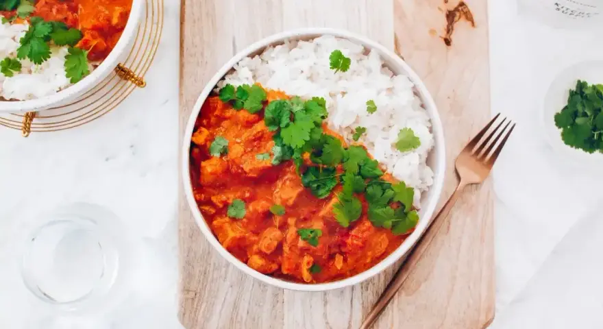 Pyszne czerwone curry z kurczakiem i ryżem, udekorowane świeżą kolendrą. Idealny przepis na obiad.