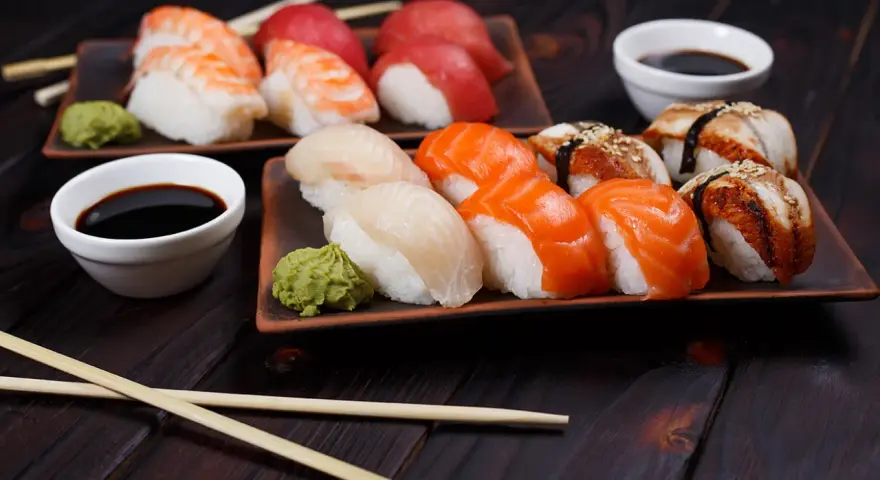 Wyśmienite japońskie sushi: nigiri z łososiem, rybą maślaną i krewetką, podane z wasabi i sosem sojowym.