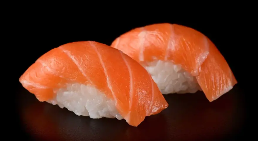 Dwa kawałki sushi z łososiem, idealna ryba do sushi, na czarnym tle.