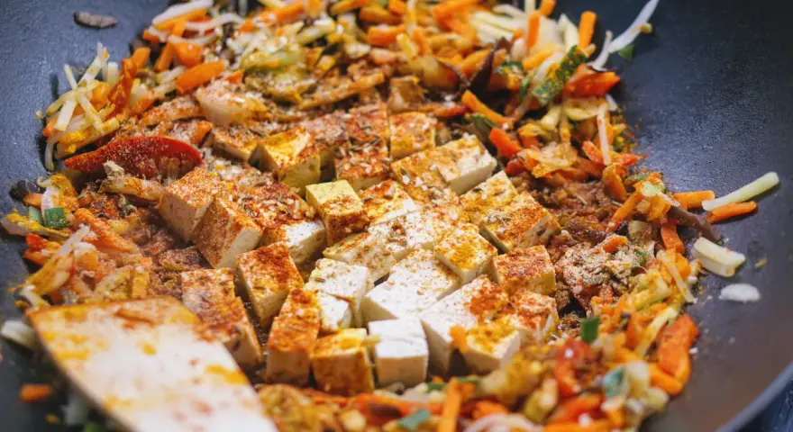 Smażone warzywa po chińsku z tofu i ryżem, doprawione kurkumą i papryką, gotowe do podania.