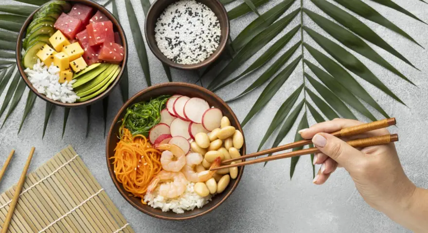 Dwie miski z pysznym sushi: jedna z tuńczykiem, awokado i ogórkiem, druga z krewetkami, fasolką i warzywami.