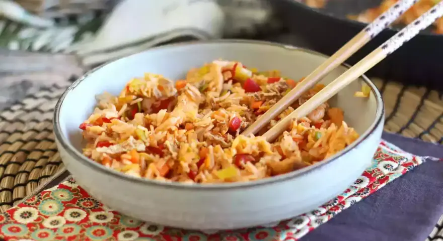 Miseczka pełna aromatycznego nasi goreng z warzywami i kawałkami mięsa, gotowa do jedzenia pałeczkami.