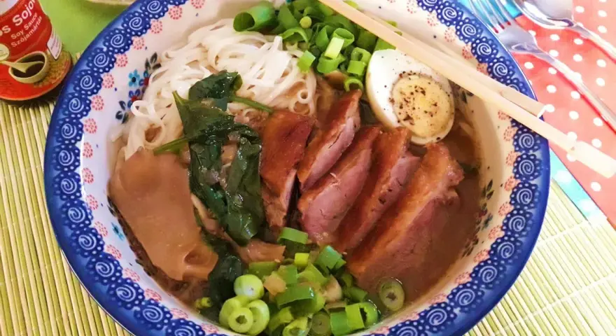 Pyszny ramen z kaczki z makaronem, jajkiem, szpinakiem i szczypiorkiem.