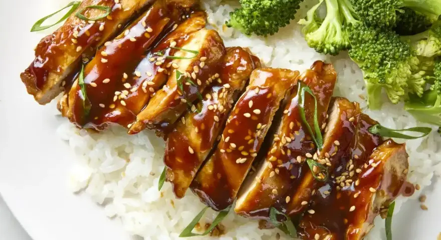 Pyszny kurczak w marynacie teriyaki, podany z ryżem i brokułami. Posypany sezamem i szczypiorkiem.