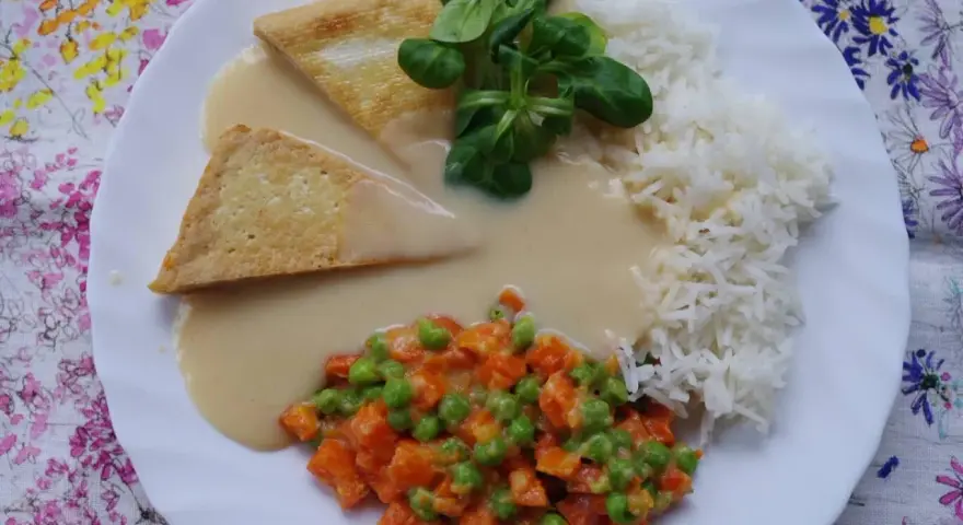 Trójkątne kawałki tofu w kremowym sosie madras, podane z ryżem i warzywami.