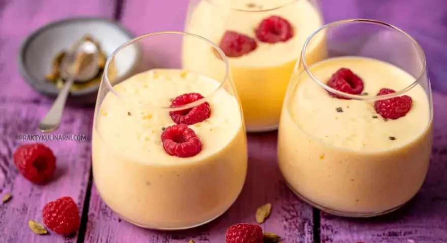 Pyszny jogurt z mango, udekorowany malinami i kardamonem, kusi swoim tropikalnym smakiem.