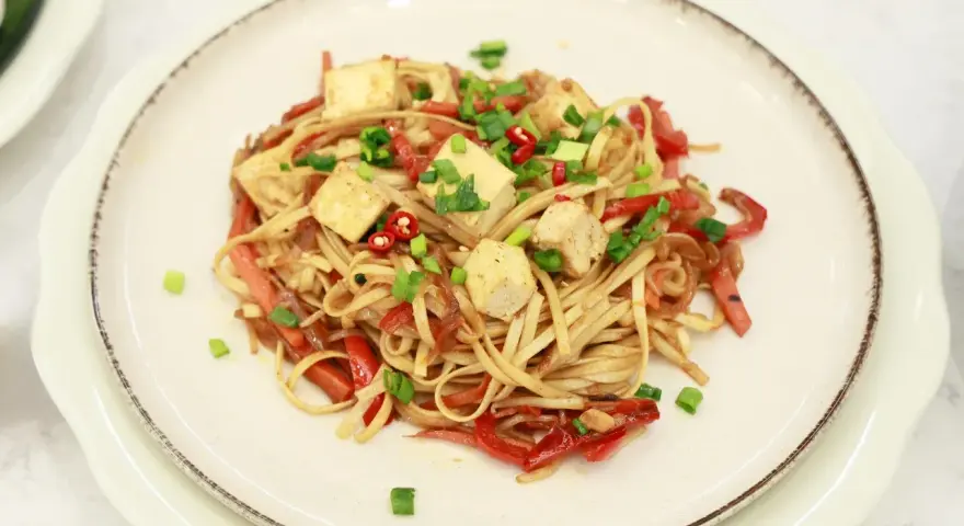 Pyszny makaron chow mein z kostkami tofu, papryką i szczypiorkiem.
