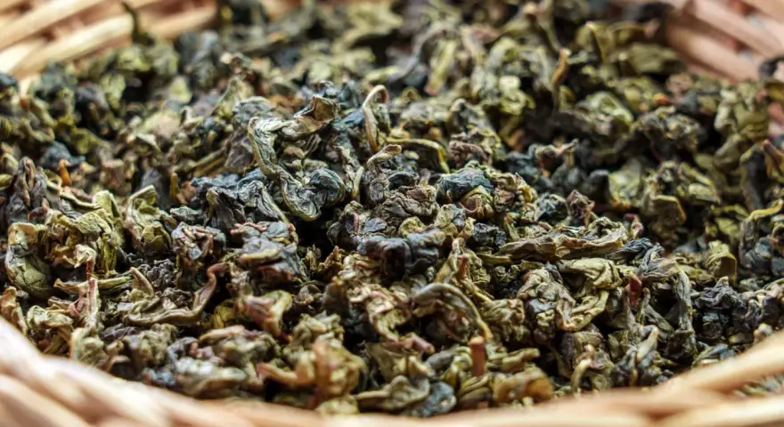 Suszone liście herbaty gunpowder w wiklinowym koszyku. Odkryj jej niezwykłe właściwości!