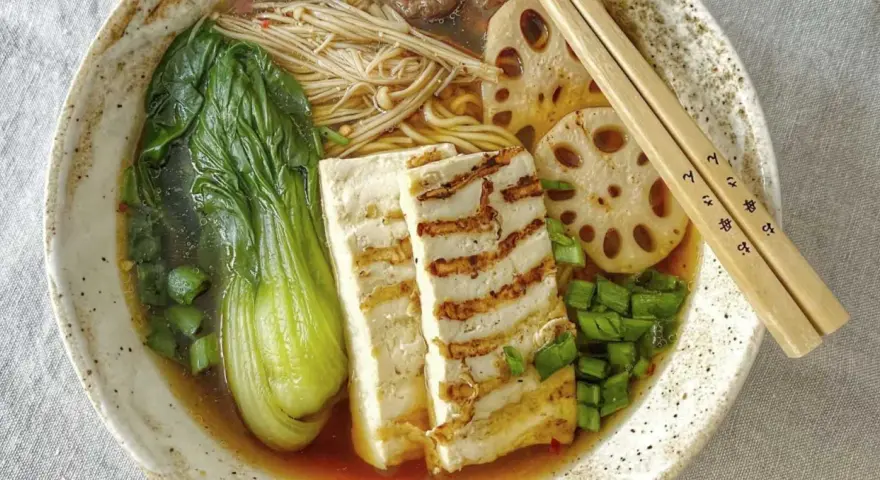 Aksamitny vege ramen z grillowanym tofu, pak choi, grzybami enoki i plasterkami lotosu. Idealny na chłodny wieczór.