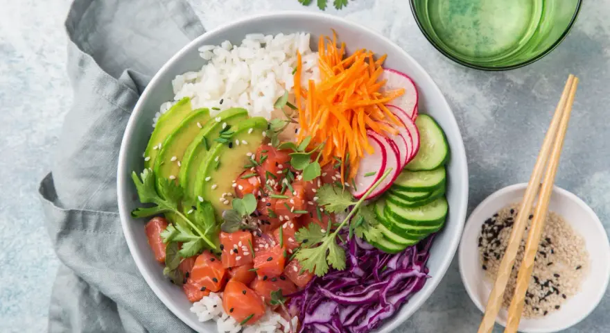 Kolorowy poke bowl: ryż, łosoś, awokado, marchewka, rzodkiewka, ogórek i czerwona kapusta. Idealny posiłek, który zaspokoi głód.