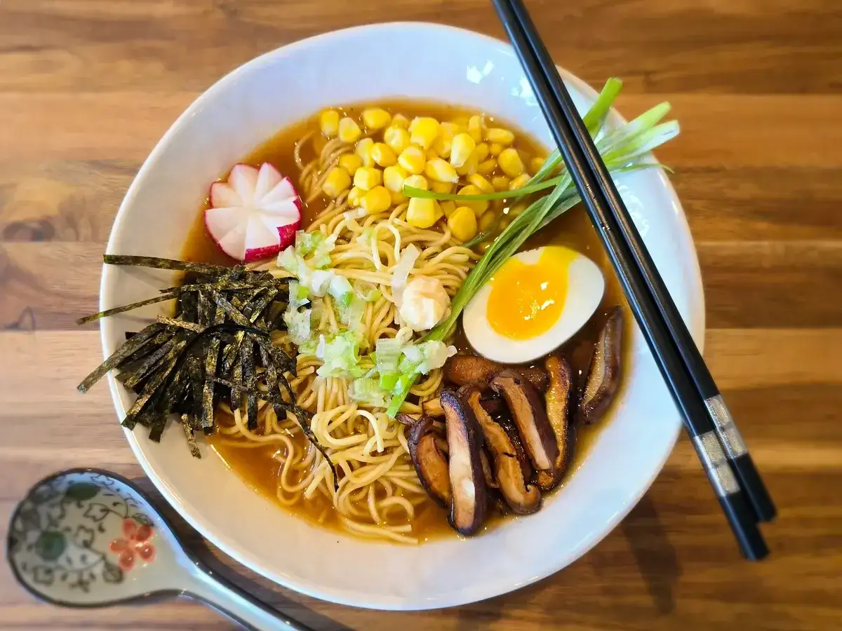 Pyszny ramen wegetariański z makaronem, jajkiem, kukurydzą, grzybami shiitake, nori i rzodkiewką.