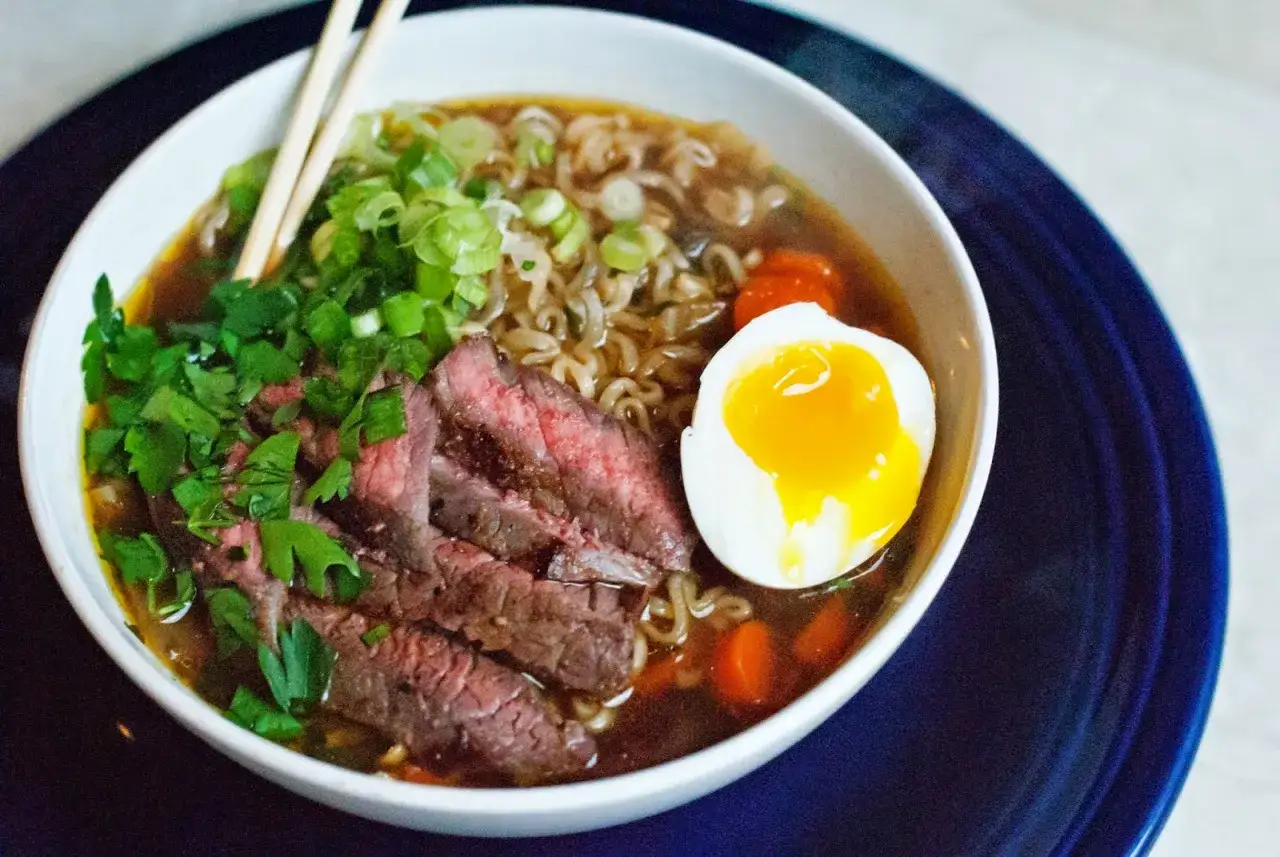 Pyszny ramen wołowy przepis: aromatyczny bulion, makaron, plastry wołowiny, jajko na pół i szczypiorek.