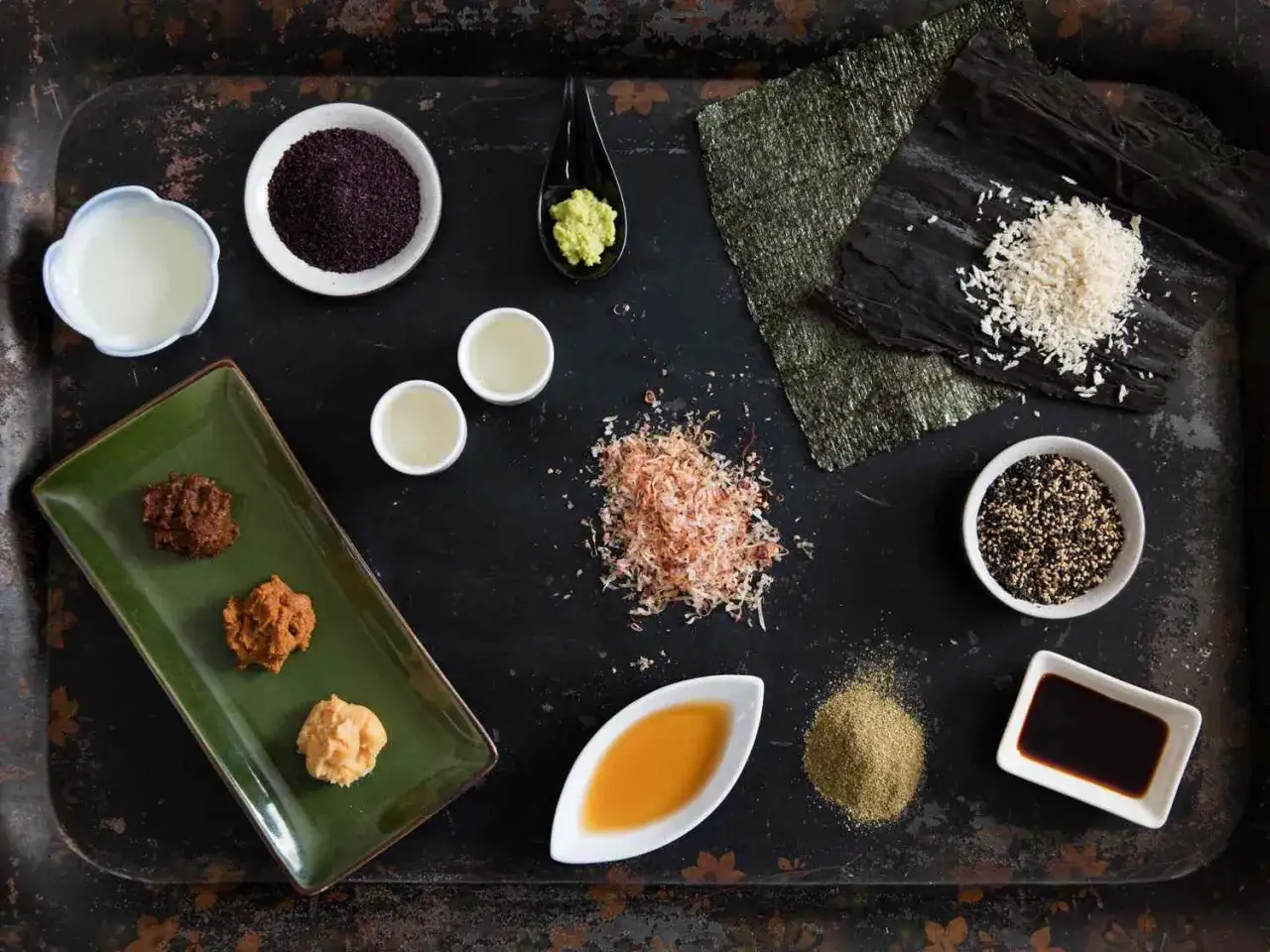 Składniki do japońskiego jedzenia: różne rodzaje pasty miso, wasabi, sos sojowy, sezam, płatki bonito, ryż i nori.