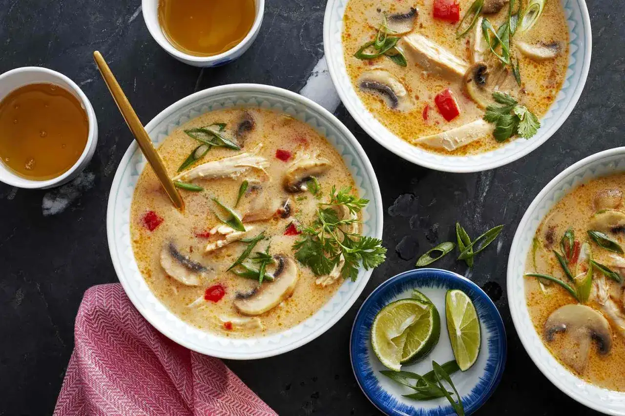 Aksamitne tom kha z kurczakiem i grzybami, ozdobione szczypiorkiem i kolendrą, podane z limonką.