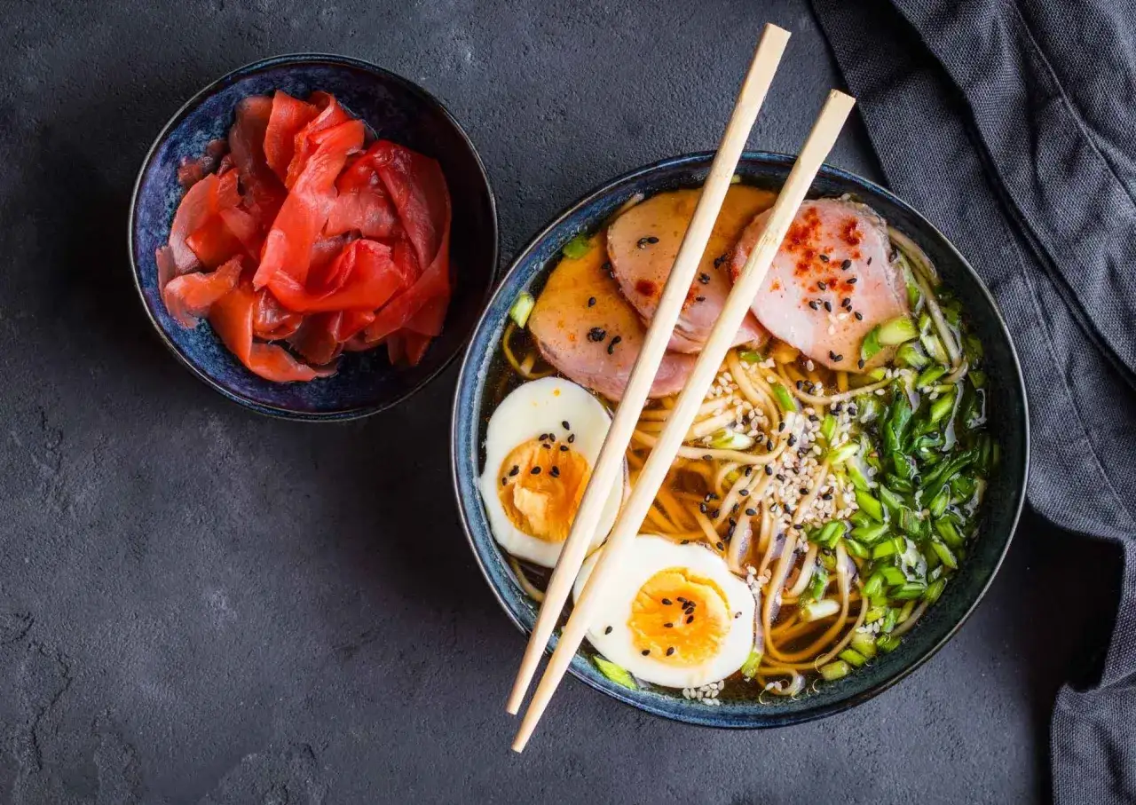 Miseczka z tradycyjnymi japońskimi potrawami: ramen z jajkiem, mięsem i szczypiorkiem, obok miseczka marynowanego imbiru.