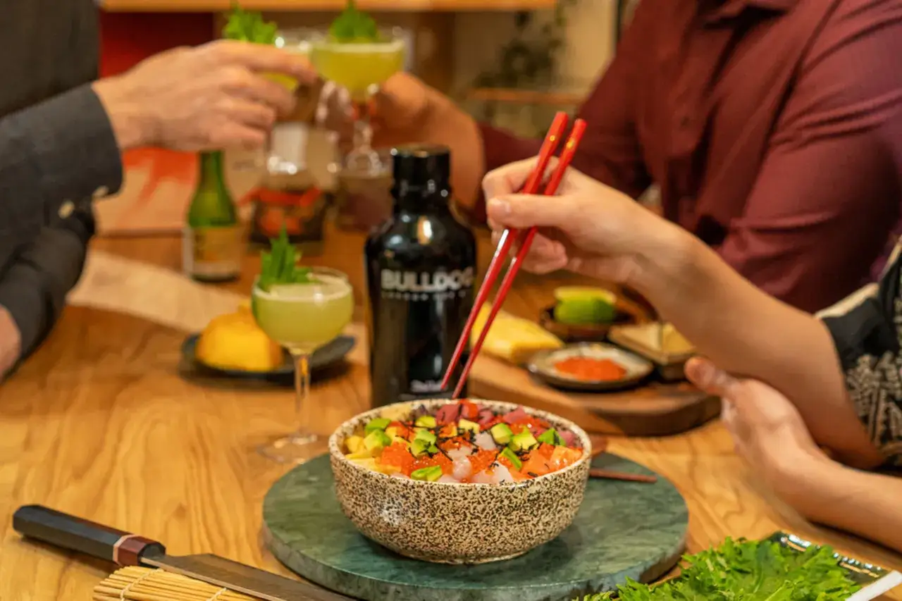 Kolorowe chirashi zushi z łososiem, tuńczykiem i awokado, podane z drinkami i butelką ginu.