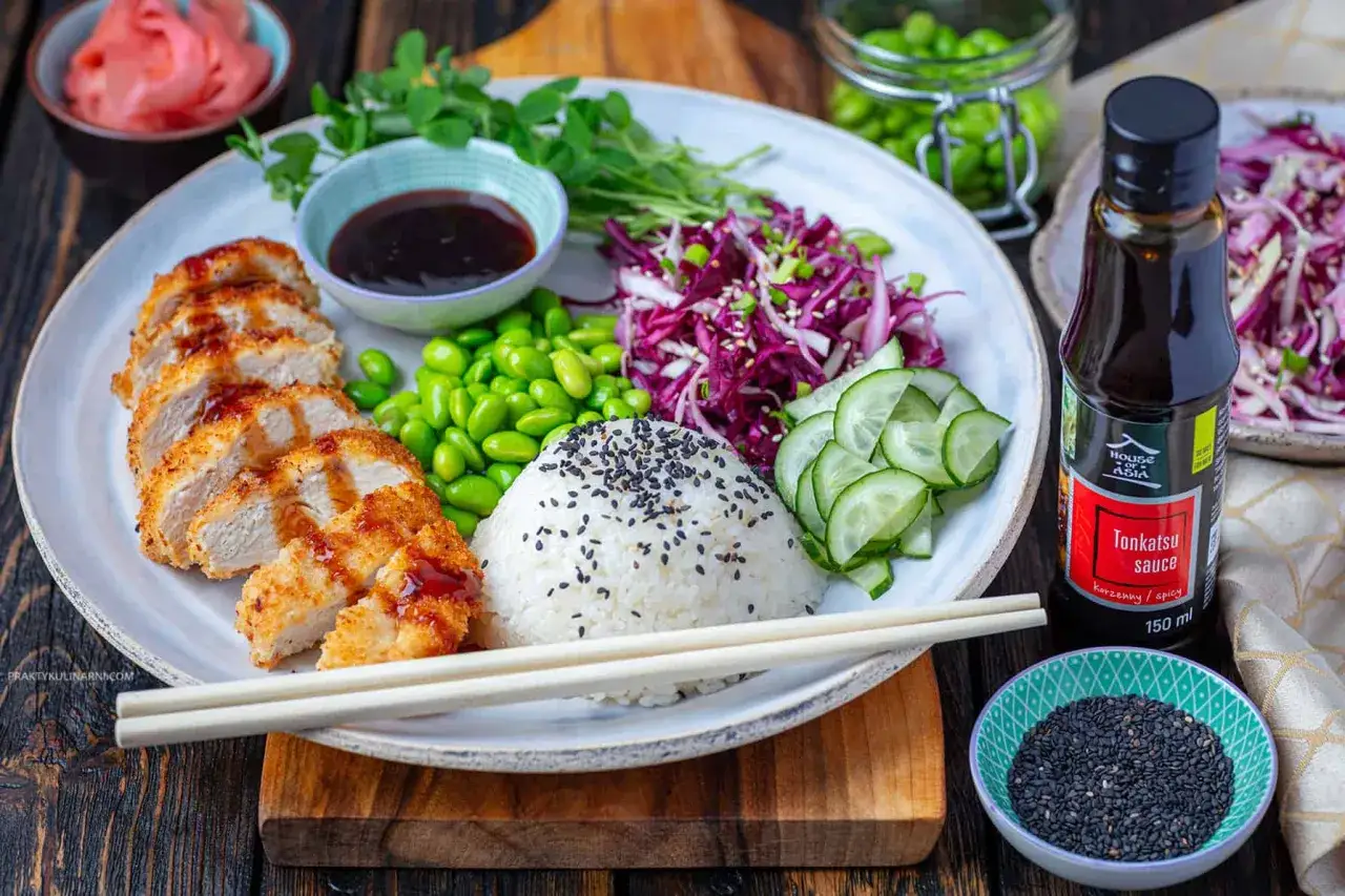 Pyszny kurczak w panierce z ryżem, edamame, czerwoną kapustą i ogórkiem, polany sosem do ryżu Tonkatsu.