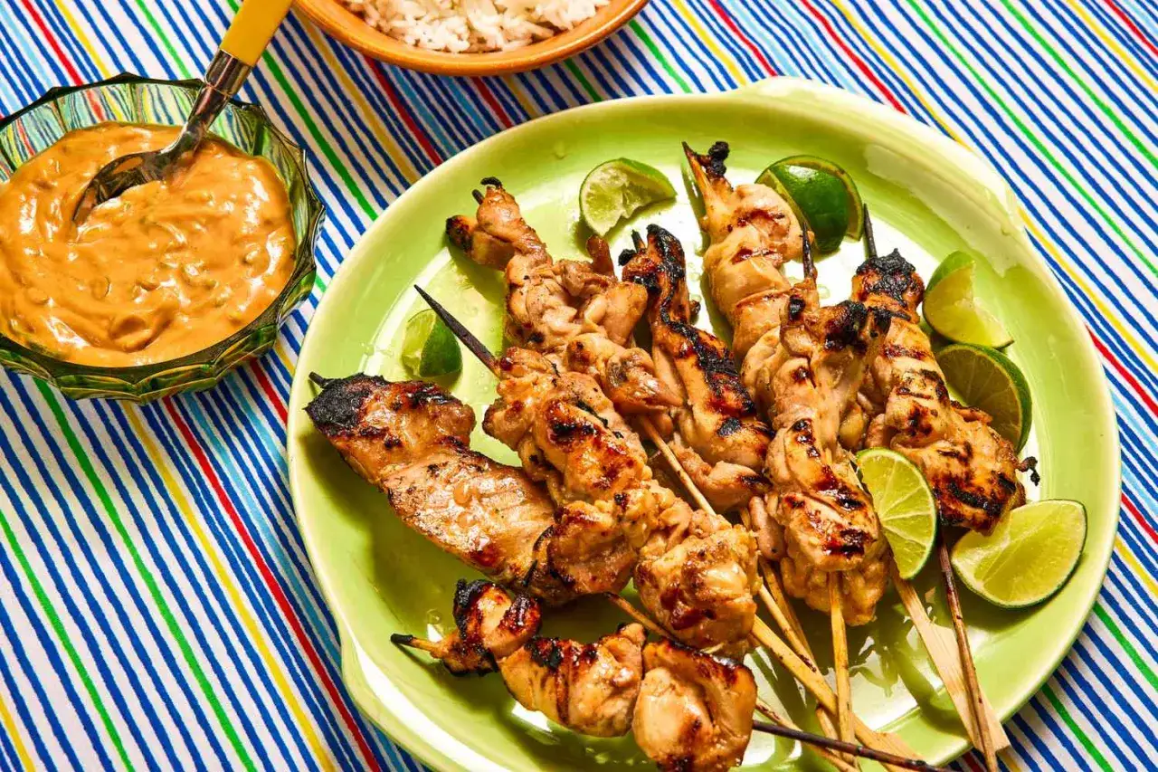 Grillowany kurczak satay na patyczkach, podany z orzechowym sosem i limonką. Idealny na letnie wieczory.