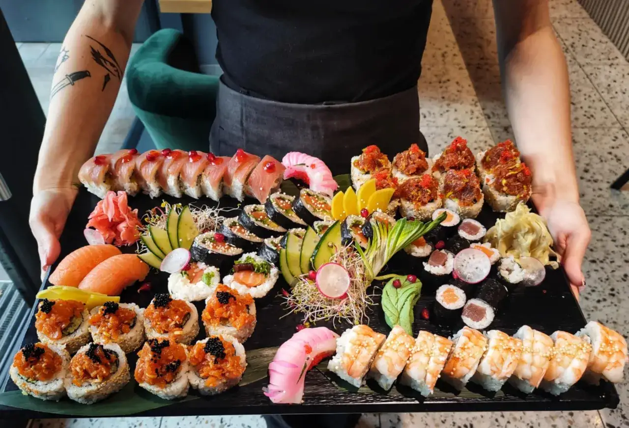 Bogata taca sushi z łososiem, krewetkami i różnymi rolkami. Idealna inspiracja, jak podawać sushi na elegancką okazję.