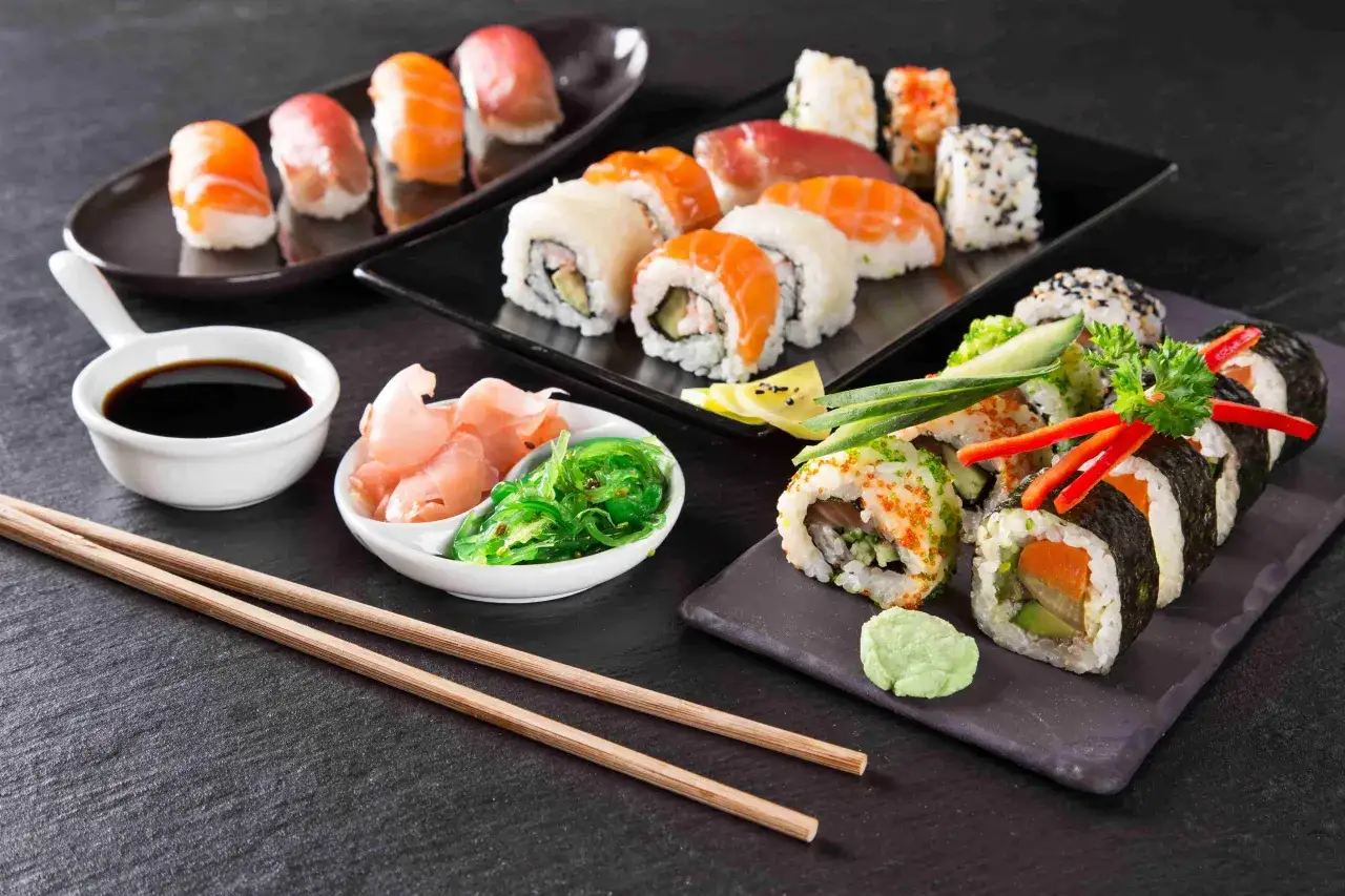 Różnorodne sushi z sezamem, łososiem i tuńczykiem, podane z imbirem, wodorostami i sosem sojowym.