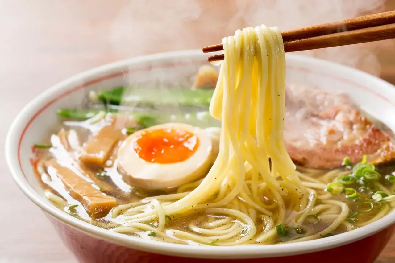 Gorący ramen z jajkiem i plastrem mięsa. Idealny makaron do ramen jest lekko falowany, idealnie wchłaniający bulion.