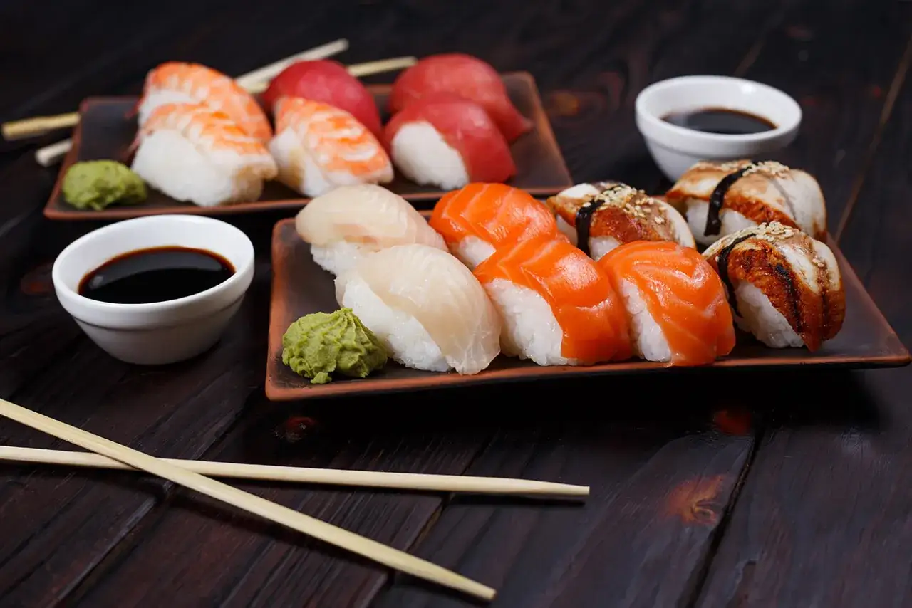 Wyśmienite sushi japońskie: nigiri z łososiem, rybą maślaną i krewetką, podane z wasabi i sosem sojowym.