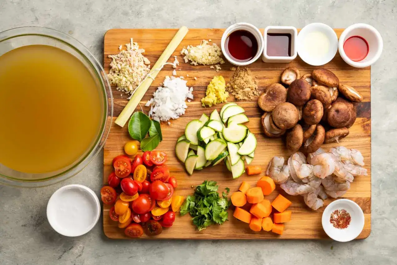 Składniki do zupy sos tom yum: bulion, trawa cytrynowa, czosnek, imbir, chili, pomidorki, cukinia, grzyby, krewetki, kolendra, marchewka, sos rybny, mleczko kokosowe.